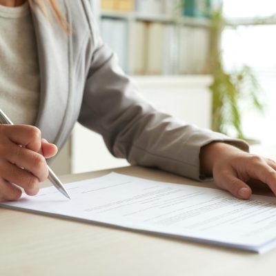 Mulher assinando documento em cima da mesa