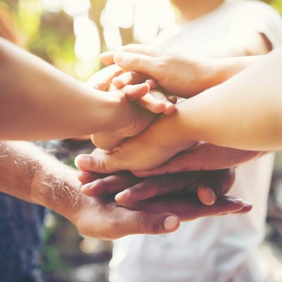 Close up of young people putting their hands together. Team with stack of hands showing unity and teamwork.